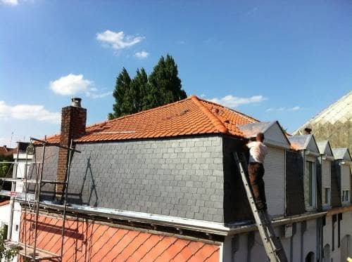 Étage sous combles habillé d'un bardage en ardoise, couvreur sur une échelle pour les finitions