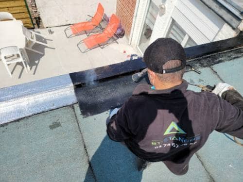 Étancheur BT'ÉTANCHE soudant au chalumeau un lé de membrane bitumineuse le long d'un relevé, sur un toit-terrasse