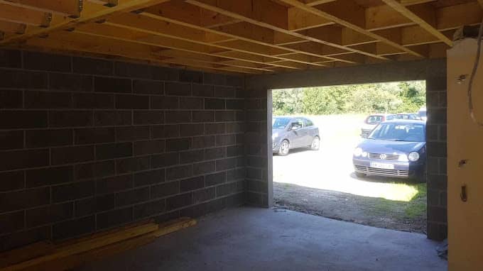 Intérieur d'un garage en parpaings, solivage bois neuf posé pour le toit
